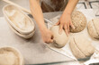 © dsheremeta - women's hands make an incision on a round dough before baking bread.