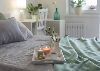 Poster - cup of coffee on wooden tray on bed with flowers and candles