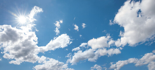 Wall Mural - cloudscape with bright sun, fluffy cumulus clouds and copy space, blue sky
