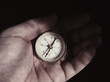 © bogdan vacarciuc - Old compass held in the palm, in semi-light. Light and shadows.