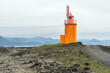 Orange lighthouse on the coast of Iceland on a cloudy and foggy summer day