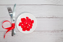 Valentines Day Meal Background With Red Ribbon, Hearts, Fork, Knife, White Plate And Napkin. Romantic Holiday Table Setting. Beautiful Background With Blank. Restaurant Concept. Flat Lay