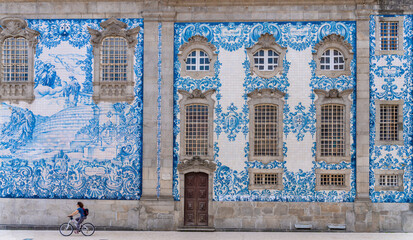 Porto, Portugal - Tourist woman cycling by side of a painted tiles church wall at Oporto old town - Traveler enjoy the city street.