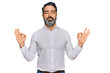 © Krakenimages.com - Middle aged man with beard wearing casual white shirt relax and smiling with eyes closed doing meditation gesture with fingers. yoga concept.