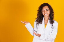 Smiling Brazilian Female Doctor In White Coat Pointing To The Side