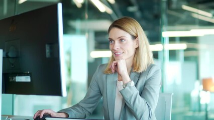 Cheerful happy woman watching. computer screen sitting at workplace in the office. Business blonde female smiling looking at text correspondence message. Read good news or dating chat on the site