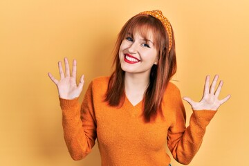 Wall Mural - Redhead young woman wearing casual orange sweater showing and pointing up with fingers number ten while smiling confident and happy.