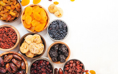 Wall Mural - Natural sun dried fruits assortment in bowls on white background. Healthy wholesome snacks. Copy space