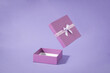Open purple gift box with ribbon isolated on background.