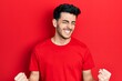 © Krakenimages.com - Young hispanic man wearing casual clothes very happy and excited doing winner gesture with arms raised, smiling and screaming for success. celebration concept.