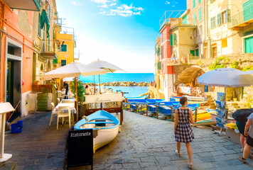 A woman walks down the boat launch at the colorful seaside village of Riomaggiore, Italy, one of the Cinque Terre villages.