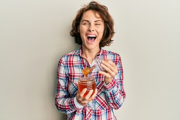 Sticker - Young brunette woman holding fresh honey smiling and laughing hard out loud because funny crazy joke.