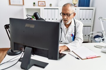 Poster - Senior grey-haired man wearing doctor uniform working at clinic