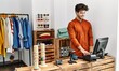 © Krakenimages.com - Young hispanic shopkeeper man smiling happy working at clothing store.