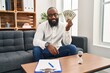 © Krakenimages.com - Young african american man psychologist holding dollars at psychology center