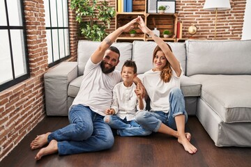 Wall Mural - Family of three doing house shape with arms smiling with an idea or question pointing finger with happy face, number one