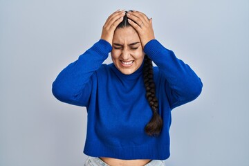 Poster - Young hispanic woman standing over isolated background suffering from headache desperate and stressed because pain and migraine. hands on head.