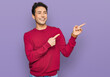 © Krakenimages.com - Young handsome man wearing casual clothes smiling and looking at the camera pointing with two hands and fingers to the side.