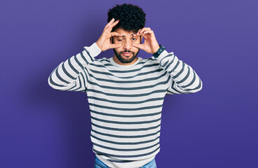 Wall Mural - Young arab man with beard wearing casual striped sweater trying to open eyes with fingers, sleepy and tired for morning fatigue