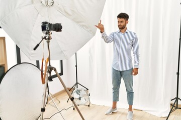 Canvas Print - Arab young man posing as model at photography studio showing middle finger, impolite and rude fuck off expression