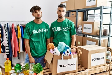 Poster - Young gay couple wearing volunteer t shirt at donations stand looking sleepy and tired, exhausted for fatigue and hangover, lazy eyes in the morning.