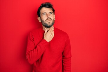 Canvas Print - Handsome man with beard wearing casual red sweater touching painful neck, sore throat for flu, clod and infection