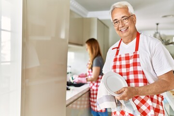 Sticker - Middle age hispanic couple smiling happy washing dishes at the kitchen.