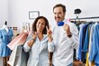 © Krakenimages.com - Hispanic middle age couple holding shopping bags and credit card smiling looking to the camera showing fingers doing victory sign. number two.