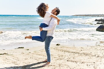 Poster - Middle age hispanic couple smiling happy and hugging at the beach.