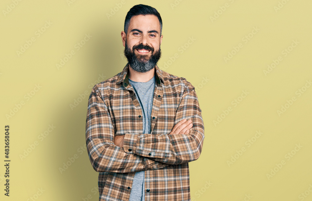 Hispanic man with beard with arms crossed gesture smiling with a happy and cool smile on face. showing teeth.