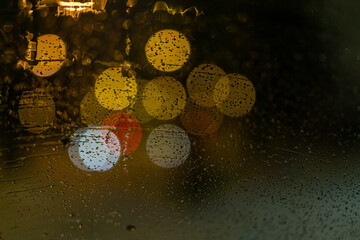 Wall Mural - blurred colored street lights from wet car's front window. water drops on the glass.