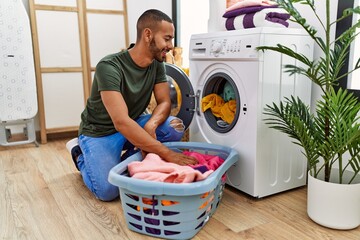 Wall Mural - Young hispanic man cleaning clothes using washing machine at laundry