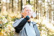 © ADDICTIVE STOCK - Senior hiker drinking water in woods