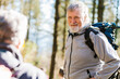 © ADDICTIVE STOCK - Elderly travelers with backpacks in forest