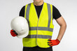 Construction helmet. Protective helmet for construction work. Worker in yellow vest holds white hard helmet. Man without face on light background. Concept - sale of uniforms for builders