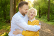 © Maria Sbytova - Loving adult son tenderly embracing his joyful elderly mother during walking at summer park.