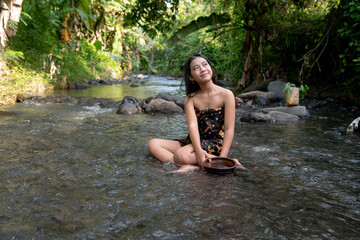 Wall Mural - Beautiful young Asian girl rests and bathes in the river