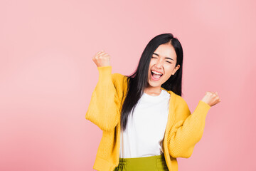 Poster - Happy Asian portrait beautiful cute young woman standing winning and surprised excited screaming open mouth raise hands, studio shot isolated pink background, Thai female wow with copy space