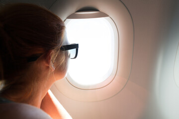 Poster - A closeup of a woman looking out of the airplane window