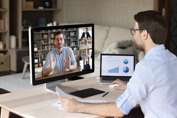 Wall Mural - side back view smiling young male employee working on different devices, holding video conference ca