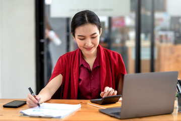 Wall Mural - Confident young Asian businesswoman sitting working at her workplace at modern office.