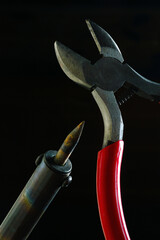 Wall Mural - wire cutters and soldering iron. dark background close-up