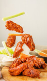 Fototapeta Tulipany - Falling chicken wings buffalo sauce with carrot and celery sticks. Fried bbq wings in flight. Traditional American cuisine concept.