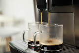 Fototapeta Mapy - Espresso machine pouring coffee into glass cups against blurred background, closeup. Space for text