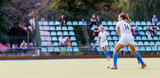 Fototapeta Sport - Young female field hockey player with the ball on the pitch.