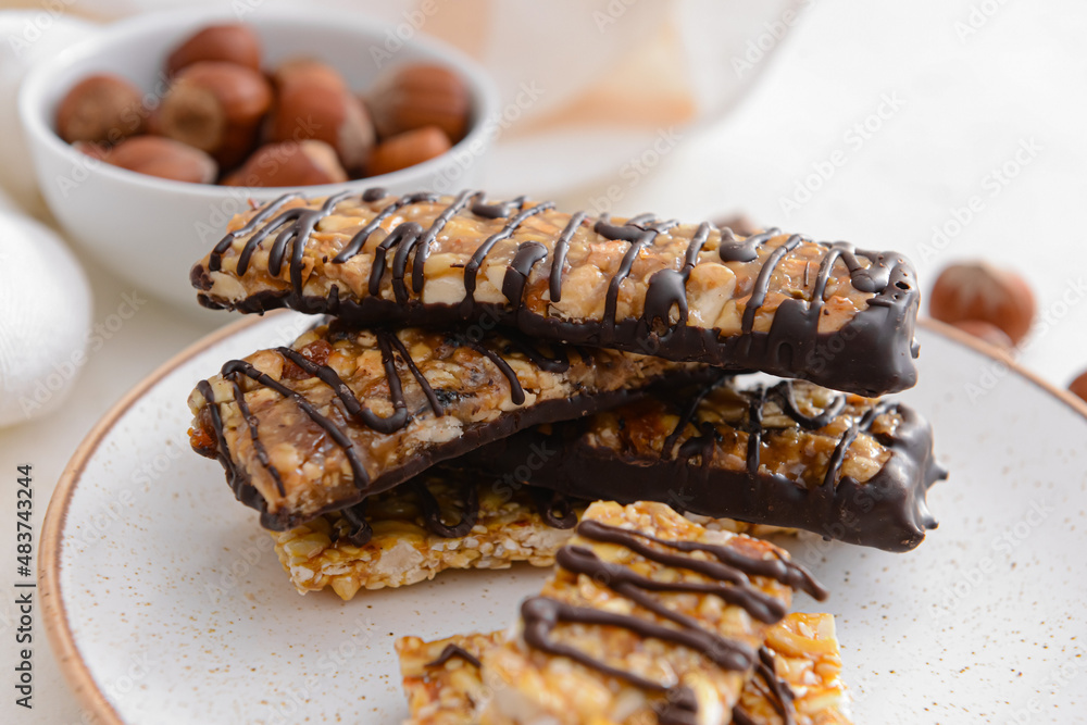 Plate with tasty chocolate nut bars on table, closeup
