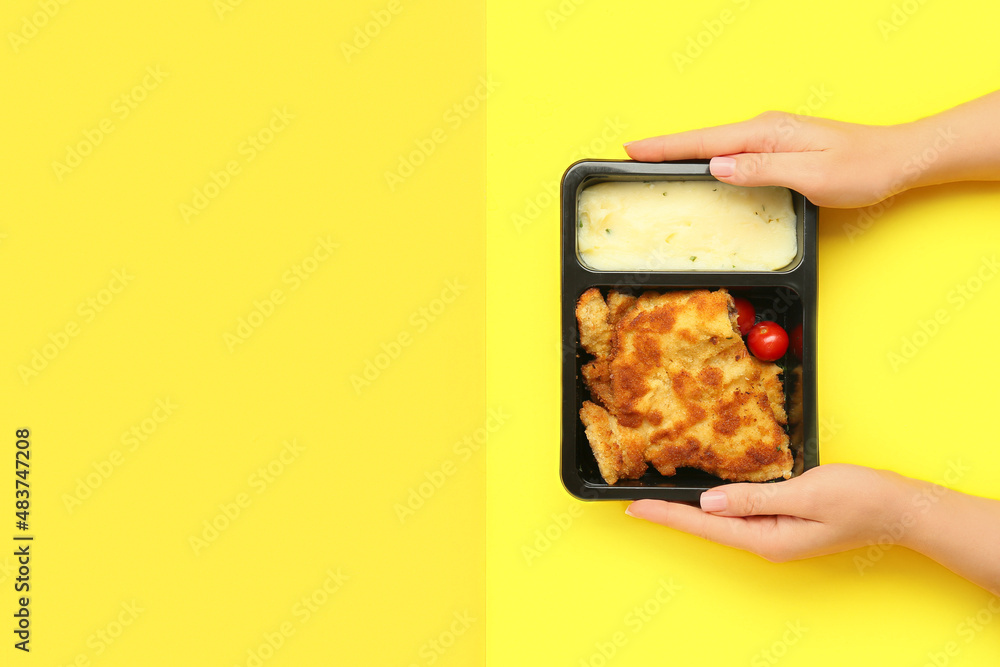 Woman holding container with delicious meals on color background