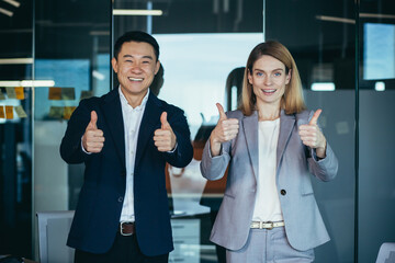 Wall Mural - Team of successful managers, group of Asian man and woman, in business clothes looking at camera and smiling holding thumbs up gesture