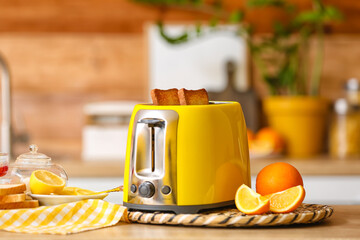 Canvas Print - Yellow toaster with bread slices and citrus fruits on table in kitchen