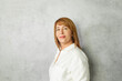 © artmim - Beautiful middle-aged woman  in a white blouse on a gray background
